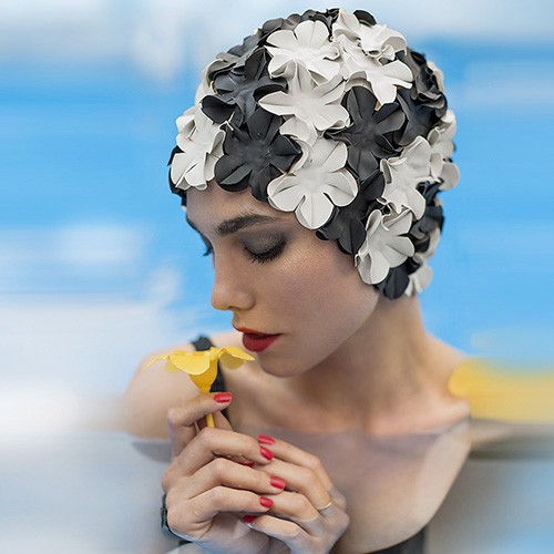 femme avec un bonnet de bain à fleurs qui rie dans une piscine